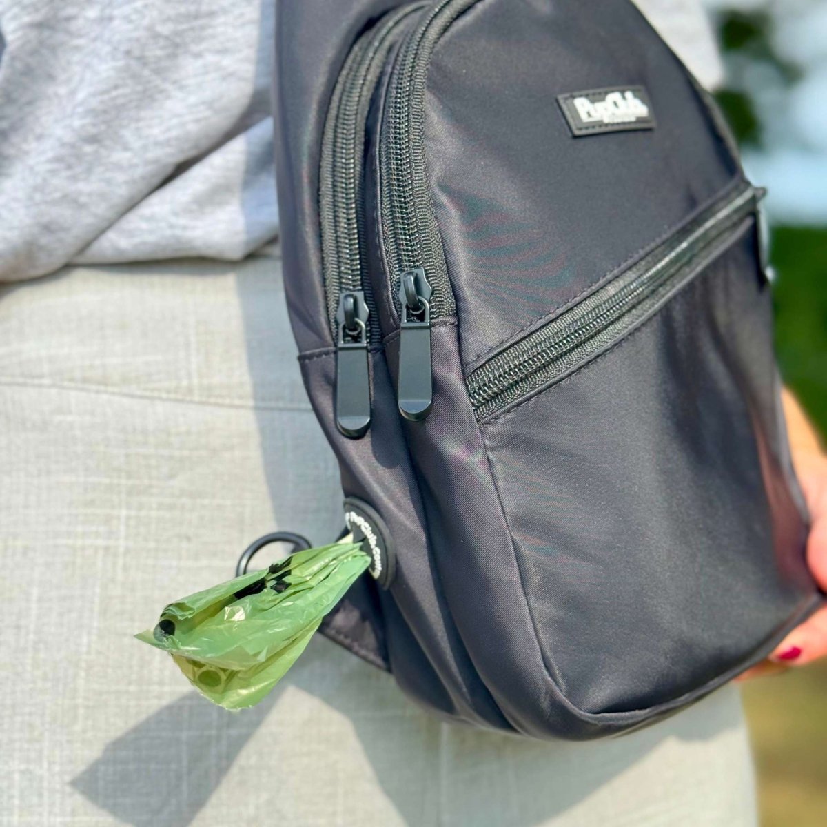 Person holding a Sling Dog Walking Bag Backpack with built in poo bag dispenser - Black - Pupclub Couture